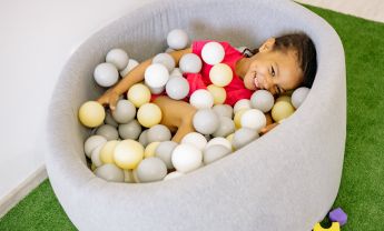 Girl With Braided Hair Playing Balls In A Tub